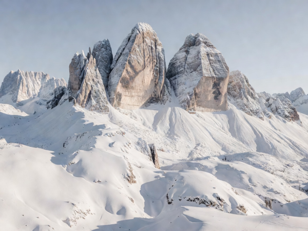 Vertical limestone rock faces of the Dolomites surrounded by snow fields