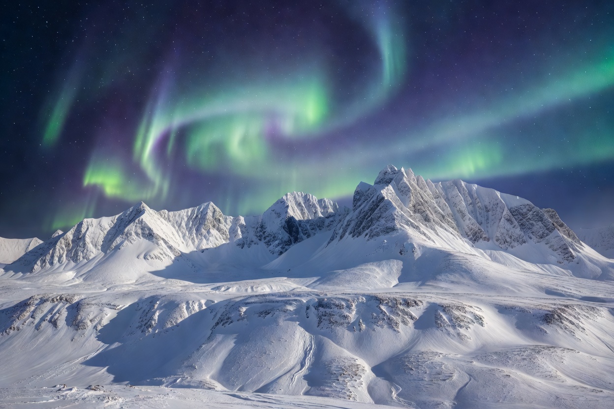 Snow-covered mountain peaks under cold northern light